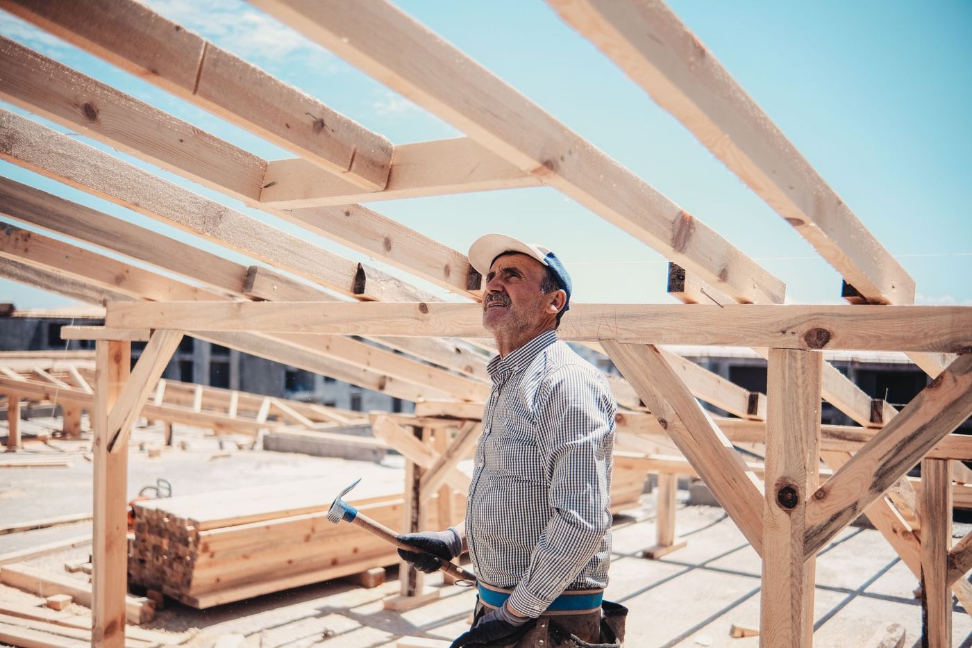 A carpenter under a timber roof frame on a building site